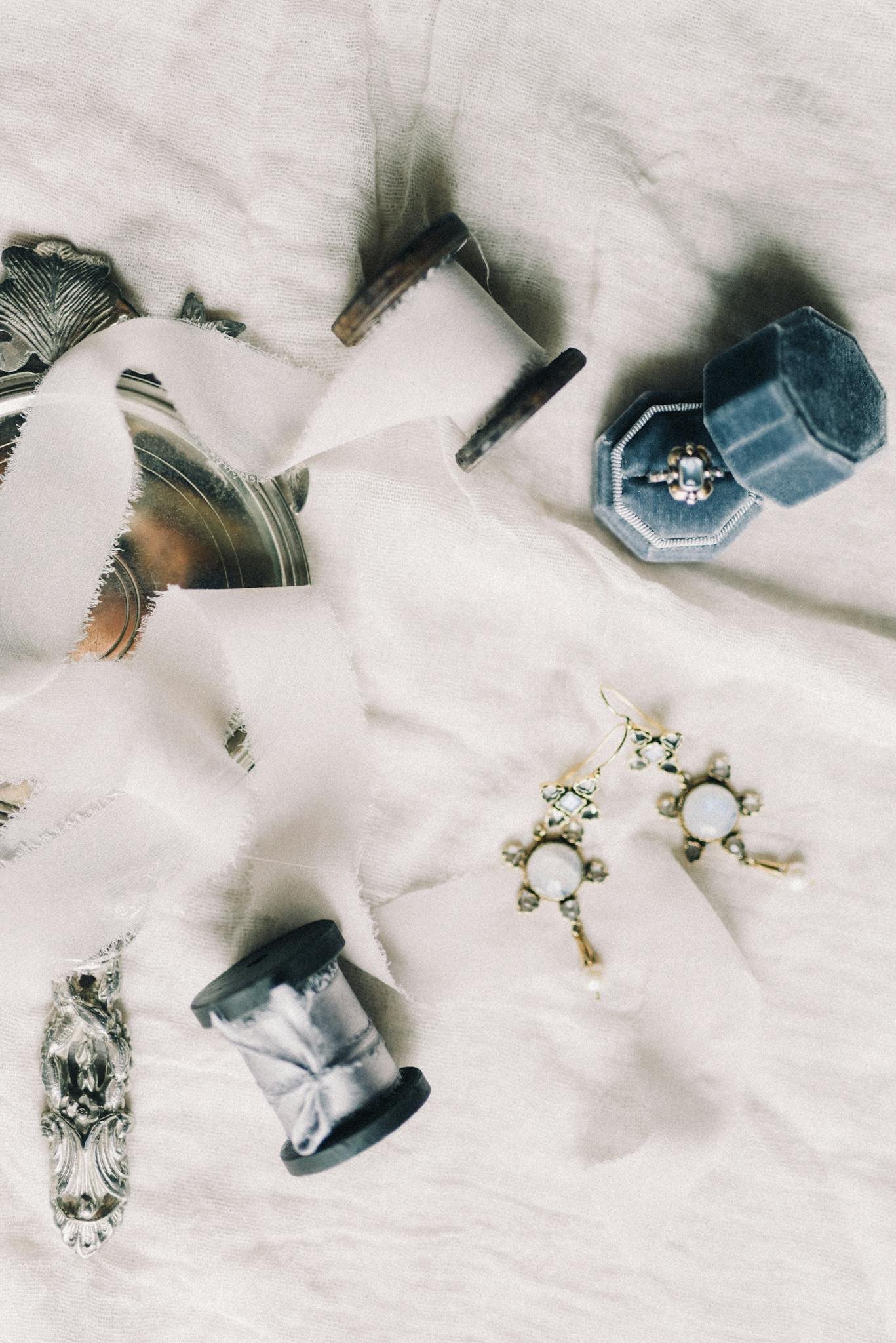 A sophisticated flat lay of earrings and blue jewelry box on silk fabric, adding a touch of elegance.