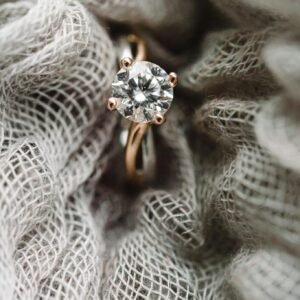 Close-up view of a sparkling diamond ring set against textured fabric, showcasing elegance and style.
