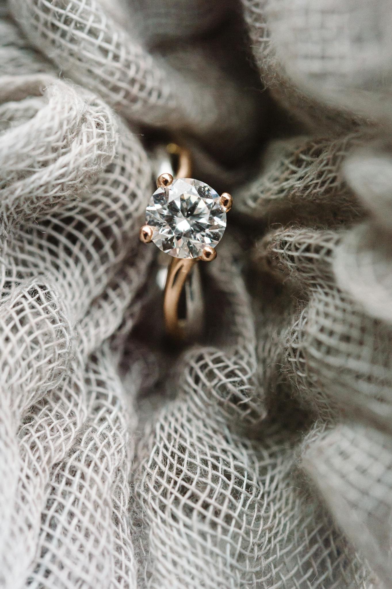 Close-up view of a sparkling diamond ring set against textured fabric, showcasing elegance and style.